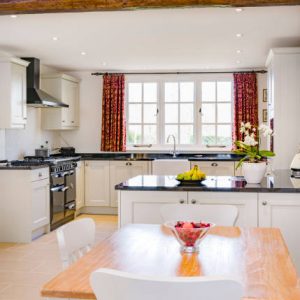 Farmhouse kitchen furniture design. UK open plan farmhouse kitchen interior with modern painted wood kitchen units, wooden breakfast table and chairs